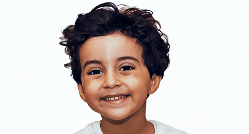 طفل يتوسط الصورة، وعلى وجهه ابتسامة.
